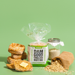 Load image into Gallery viewer, English muffins, sourdough package, and jar on a green background
