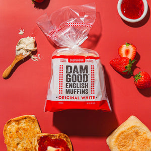 Packaged English muffins with toast and strawberries on a red background