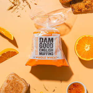 Packaged Whole Wheat Dam Good English Muffins with oranges on a yellow background