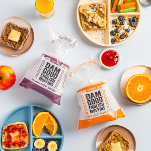 Assorted breakfast items including Dam Good English Muffins, fruit, and spreads on a white surface.